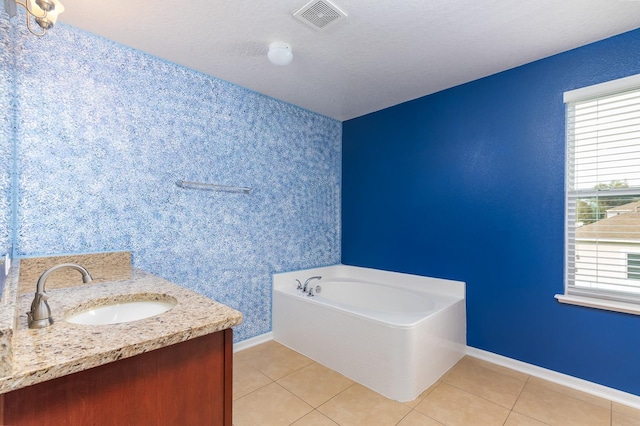 bathroom with vanity, a bath, tile patterned flooring, and a textured ceiling