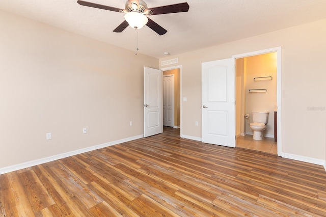 unfurnished bedroom with connected bathroom, hardwood / wood-style floors, and ceiling fan