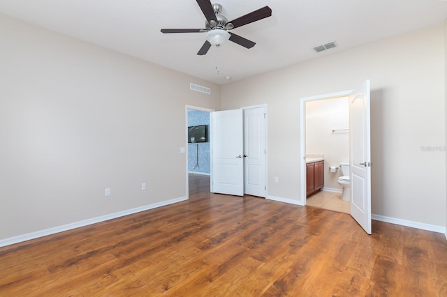 24448 SW 8th Pl, Newberry, FL 32669 - unfurnished bedroom featuring ensuite bathroom, baseboards, wood finished floors, and a ceiling fan
