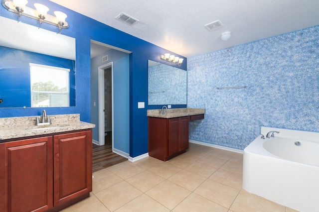 24448 SW 8th Pl, Newberry, FL 32669 - bathroom with two vanities, a textured ceiling, a bath, baseboards, and tile patterned flooring