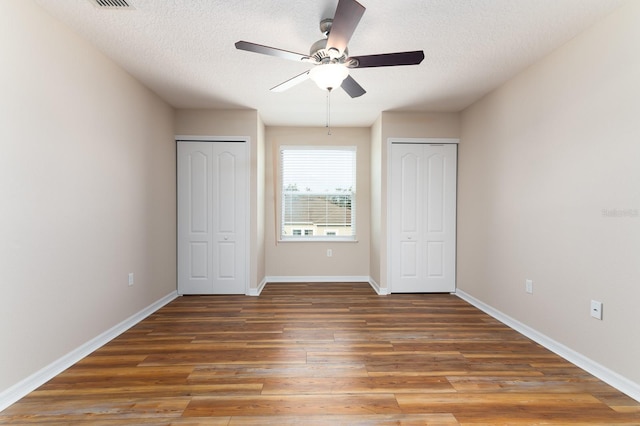 24448 SW 8th Pl, Newberry, FL 32669 - unfurnished bedroom featuring multiple closets, wood finished floors, a textured ceiling, baseboards, and ceiling fan