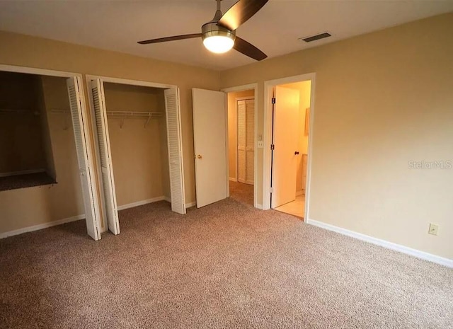 unfurnished bedroom featuring ceiling fan, light colored carpet, and multiple closets