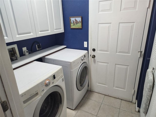 laundry room featuring washer and clothes dryer, cabinets, and light tile patterned flooring