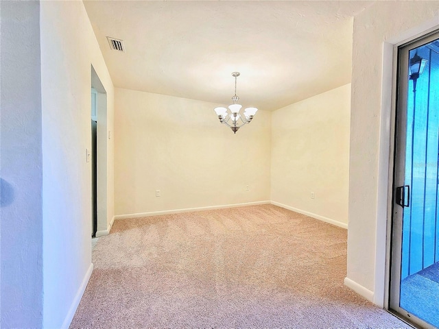 carpeted empty room featuring an inviting chandelier