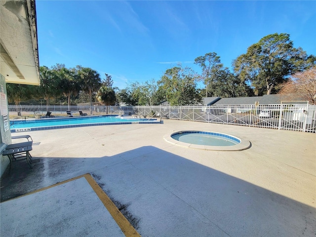 view of swimming pool featuring a hot tub and a patio area