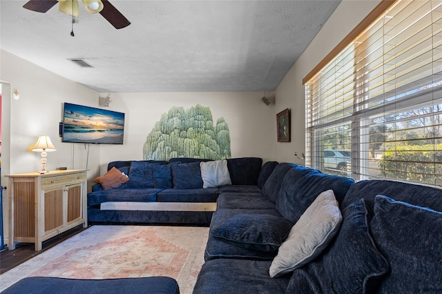 living room featuring ceiling fan and a textured ceiling