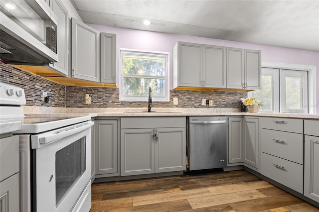 kitchen featuring stainless steel appliances, dark hardwood / wood-style flooring, and gray cabinets