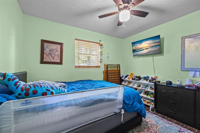 bedroom with ceiling fan, dark wood-type flooring, and a textured ceiling