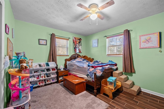 bedroom featuring multiple windows, ceiling fan, dark hardwood / wood-style flooring, and a textured ceiling