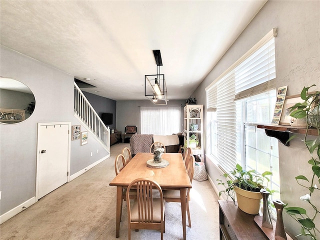 carpeted dining space featuring an inviting chandelier