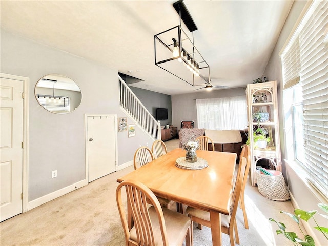 dining space featuring light carpet and ceiling fan