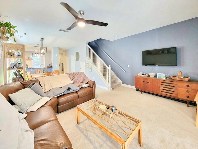 living room featuring ceiling fan with notable chandelier and light colored carpet