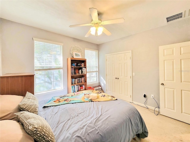 bedroom with ceiling fan, a closet, and light carpet