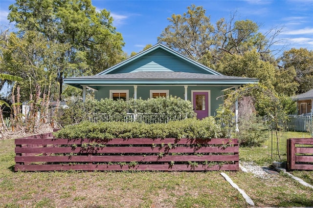 view of side of property with a porch, a shingled roof, and fence