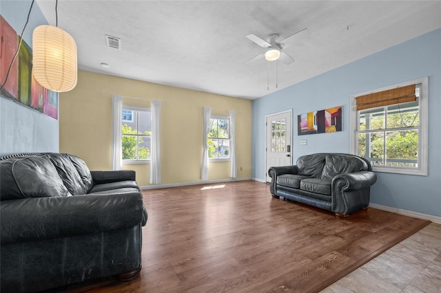 living room featuring visible vents, wood finished floors, baseboards, and ceiling fan