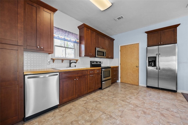 kitchen with visible vents, a sink, decorative backsplash, light countertops, and stainless steel appliances