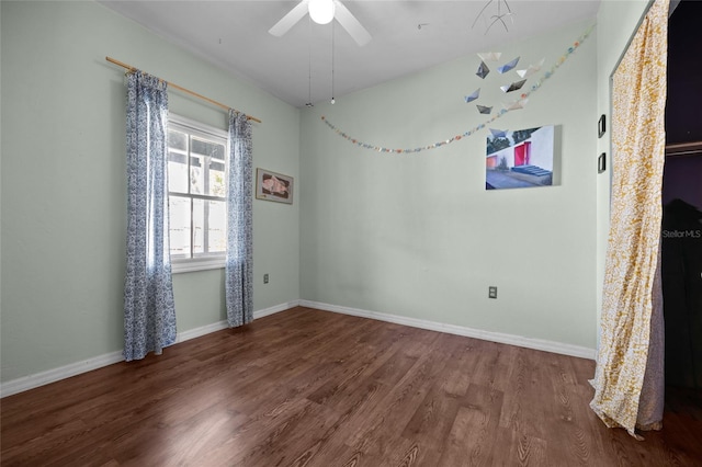 empty room featuring baseboards, wood finished floors, and a ceiling fan