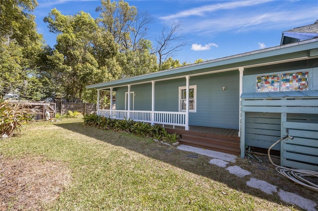 exterior space featuring a porch, a lawn, and fence