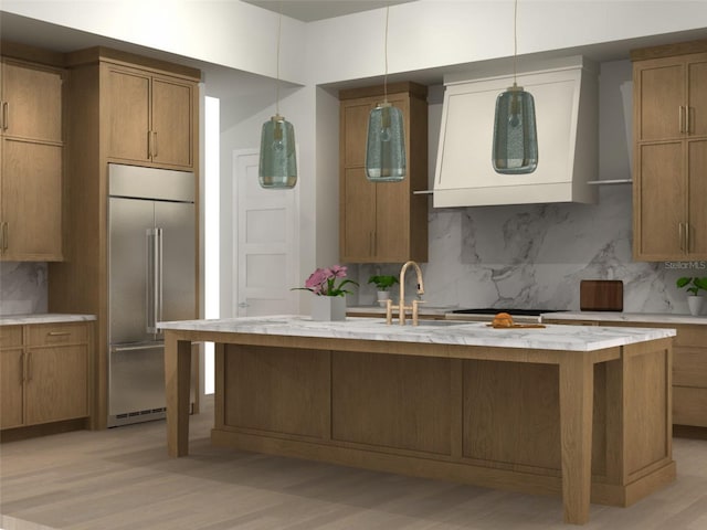 kitchen featuring sink, a kitchen island with sink, stainless steel built in refrigerator, decorative backsplash, and wall chimney exhaust hood