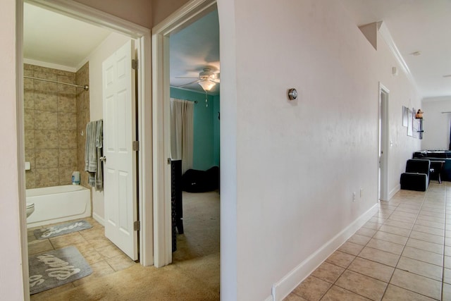 corridor with light tile patterned floors and crown molding