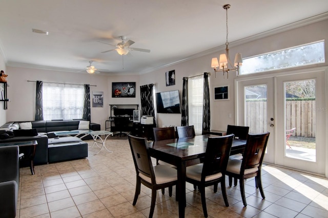 dining area with crown molding, ceiling fan with notable chandelier, light tile patterned floors, and french doors