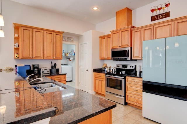 kitchen featuring sink, light tile patterned floors, washer and clothes dryer, stainless steel appliances, and dark stone counters