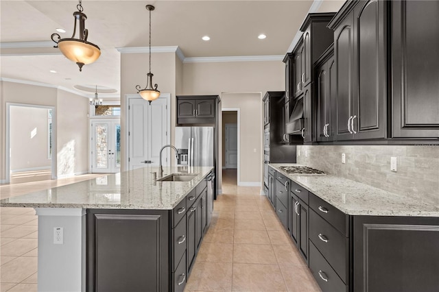 kitchen with pendant lighting, appliances with stainless steel finishes, sink, and a kitchen island with sink