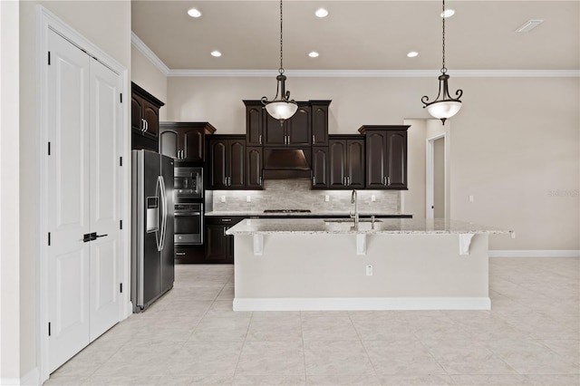 kitchen with a kitchen island with sink, light stone countertops, decorative light fixtures, and stainless steel appliances