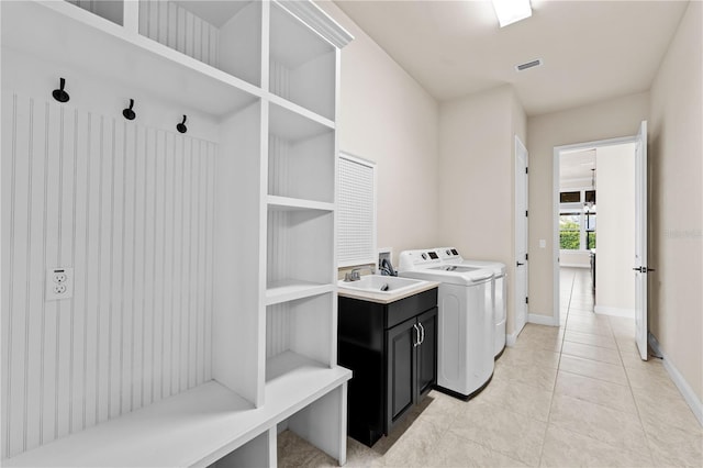 clothes washing area featuring cabinets, sink, washing machine and dryer, and light tile patterned floors