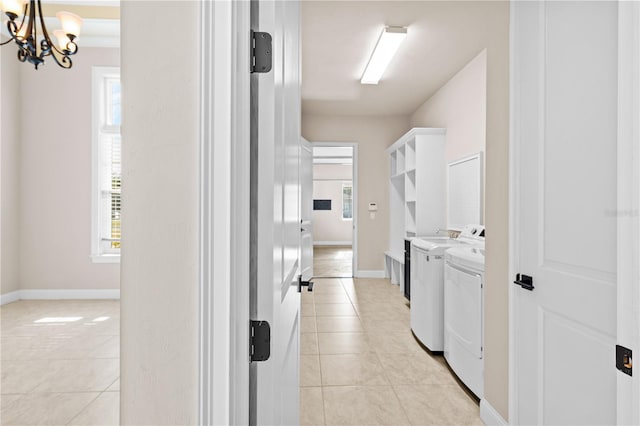 clothes washing area with a notable chandelier, plenty of natural light, washing machine and dryer, and light tile patterned floors