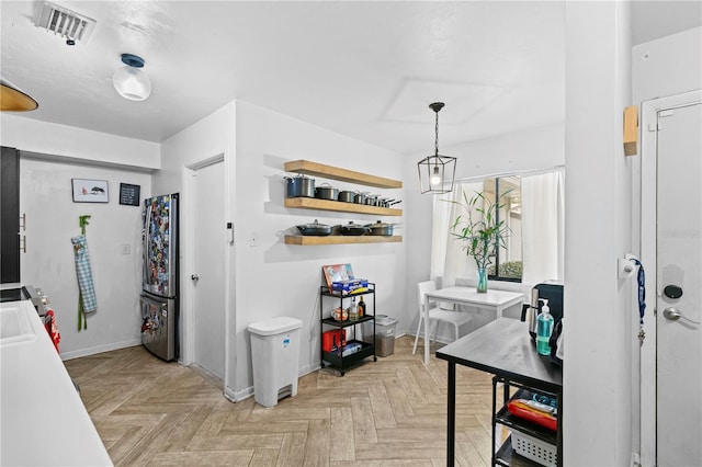 kitchen with pendant lighting, light parquet flooring, stainless steel fridge, and sink