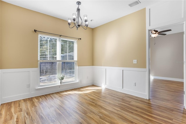 empty room featuring ceiling fan with notable chandelier and light hardwood / wood-style flooring