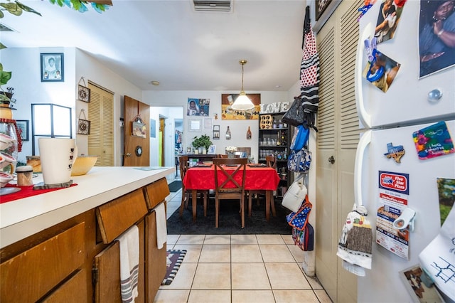 kitchen with light tile patterned floors, decorative light fixtures, and white fridge