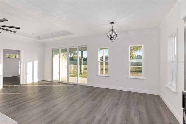 unfurnished living room with a raised ceiling, crown molding, dark wood-type flooring, and ceiling fan with notable chandelier