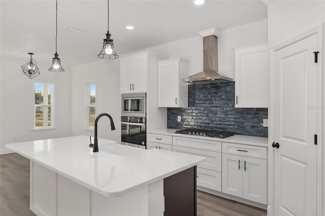 kitchen with white cabinetry, wall chimney exhaust hood, stainless steel appliances, and an island with sink