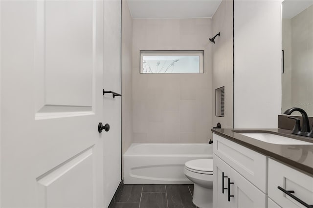 full bathroom featuring tiled shower / bath combo, vanity, and toilet