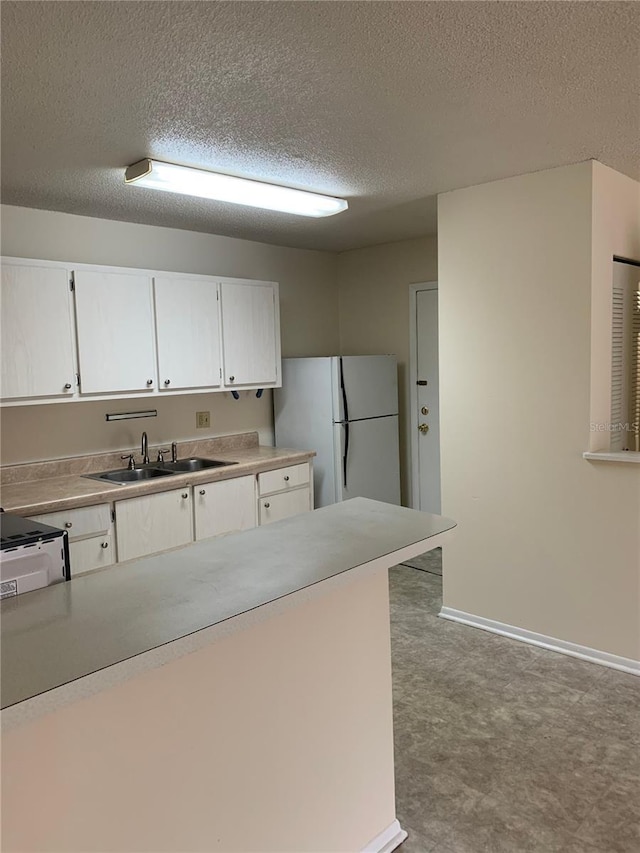 kitchen featuring white cabinetry, range, sink, and white fridge