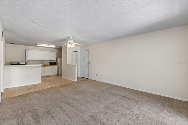 1700 SW 16th Ct Unit J-23, Gainesville, FL 32608 - unfurnished living room with light carpet, a ceiling fan, a textured ceiling, and baseboards