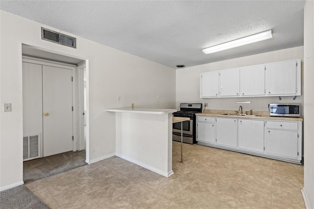 1700 SW 16th Ct Unit J-23, Gainesville, FL 32608 - kitchen with stainless steel appliances, a sink, a textured ceiling, white cabinetry, and light countertops