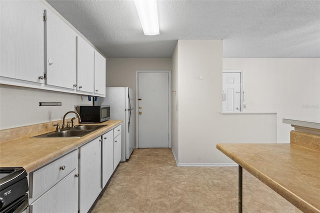 1700 SW 16th Ct Unit J-23, Gainesville, FL 32608 - kitchen with stainless steel microwave, a sink, light countertops, white cabinetry, and a textured ceiling
