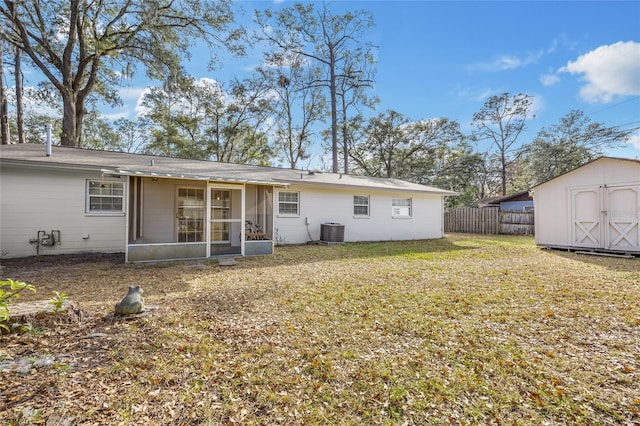 back of property with a sunroom, central AC, a shed, and a lawn