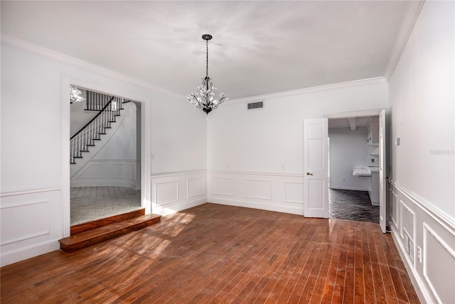 empty room with crown molding, dark hardwood / wood-style floors, and a chandelier