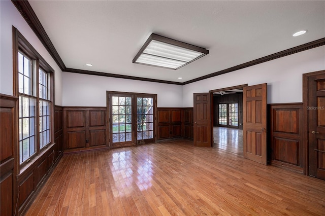 empty room featuring light hardwood / wood-style flooring, ornamental molding, french doors, and a healthy amount of sunlight