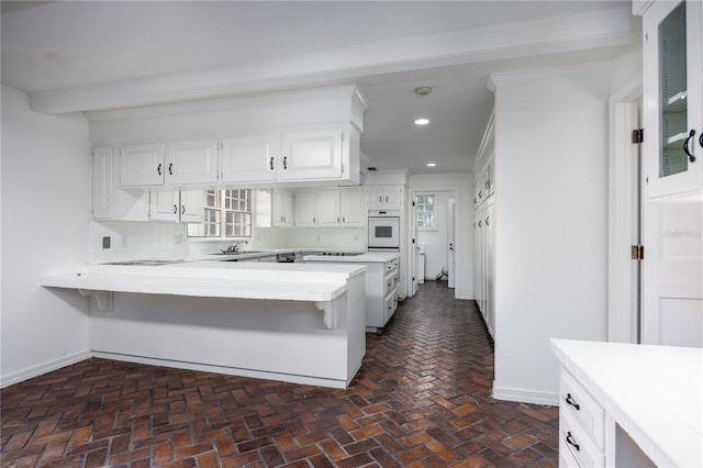 kitchen featuring white cabinets, oven, a kitchen breakfast bar, and kitchen peninsula