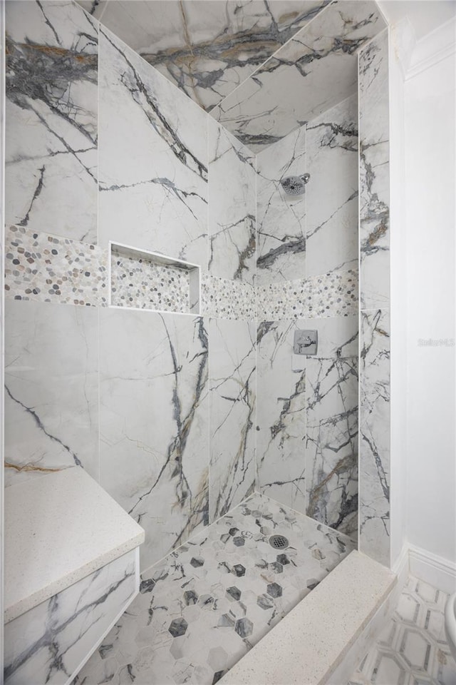 bathroom with ornamental molding and tiled shower