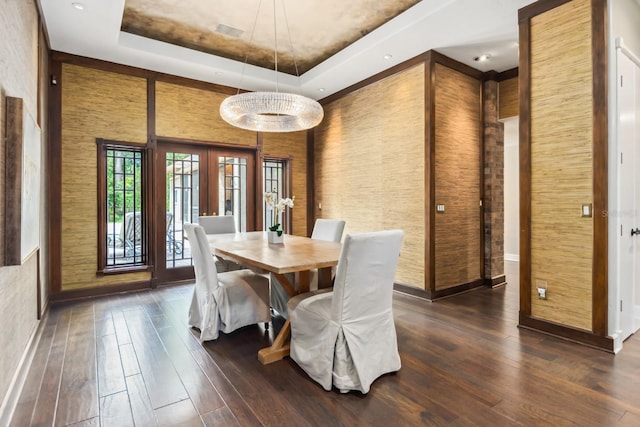 dining room featuring dark wood-type flooring, a raised ceiling, french doors, and a high ceiling