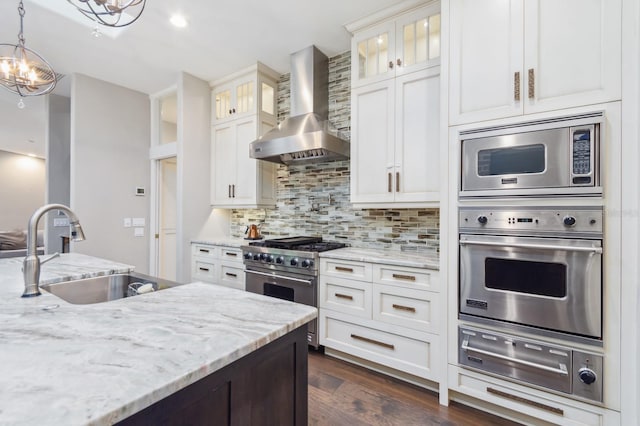 kitchen featuring appliances with stainless steel finishes, sink, white cabinets, and wall chimney exhaust hood