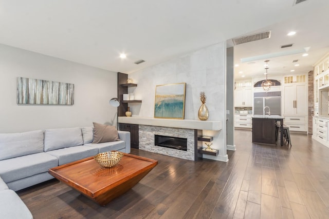 living room featuring dark hardwood / wood-style flooring, sink, and a stone fireplace