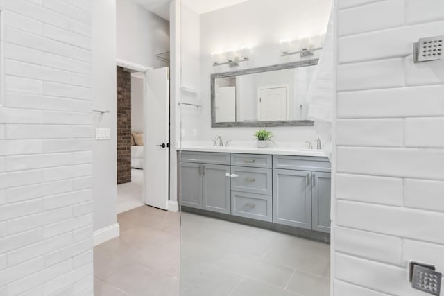 bathroom featuring vanity, tile patterned floors, and brick wall