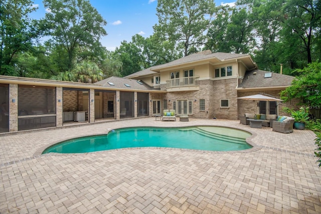 view of pool with a patio area, a sunroom, outdoor lounge area, and french doors